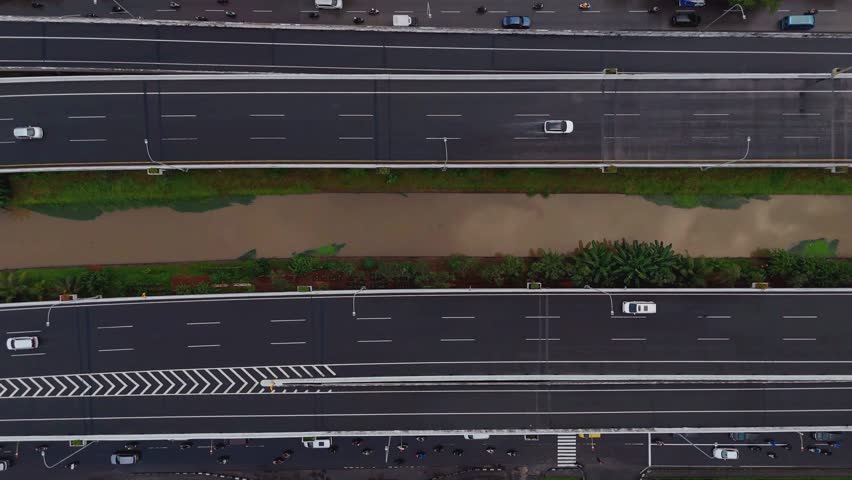 Aerial view of cars driving on a highway with residential buildings and a cloudy sky in the background
