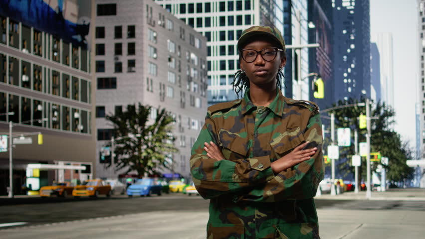 Portrait of african american army officer with arms crossed in city center, disciplined military recruit strolling around town and exploring metropolitan area in camouflage uniform.