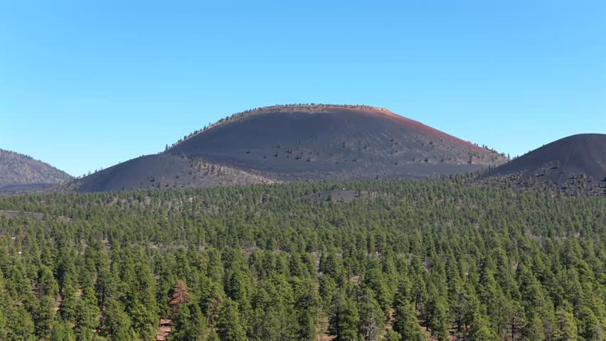 4K aerial drone shot of ancient ponderosa pine forest and volcanic cinder hills near Flagstaff Arizona. Scenic southwestern wilderness landscape for travel tourism and destination marketing B-roll.