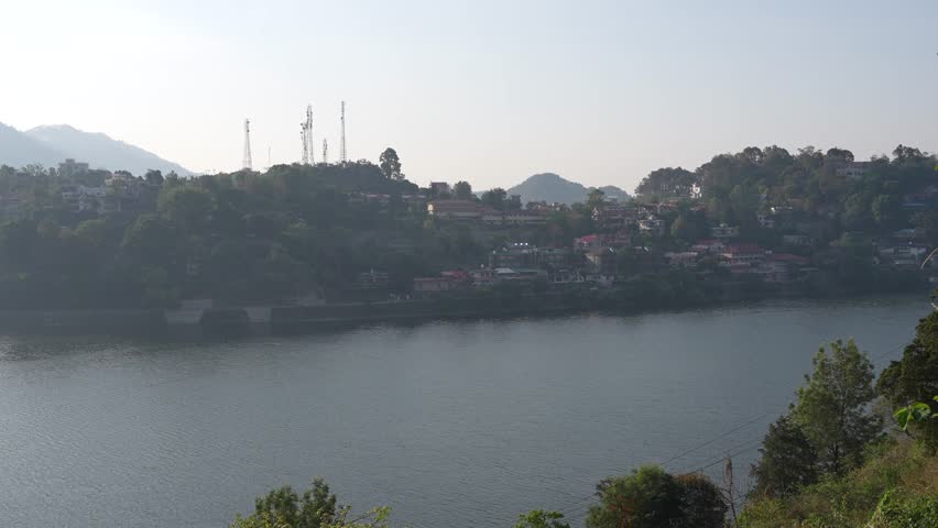 Wide view of Bhimtal Lake with distant hills and light clouds in sky.