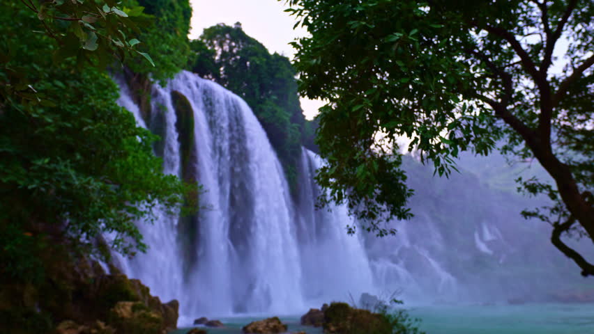 Travelers trek through scenic valleys and traditional villages toward the mighty Ban Gioc Falls, where roaring water and stunning natural beauty create an unforgettable landscape.