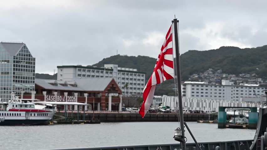 Japanese maritime self-defense force ensign flying on a warship in sasebo port, japan