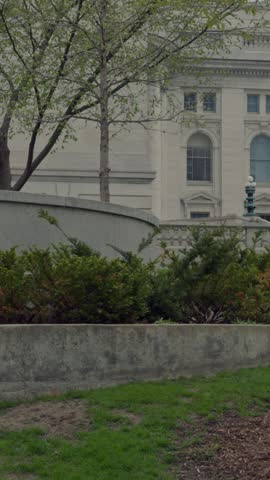 Vertical cinematic gimbal shot tilting up and panning left outside Wisconsin State Capitol showing historic architecture in daylight