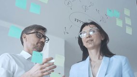 Business colleagues collaborating on an innovative project, brainstorming ideas and developing a strategic plan using sticky notes on a clear glass whiteboard - Powered by Shutterstock - Get 15% off with code: PIKWIZARD15