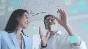 Business colleagues collaborating on an innovative project, brainstorming ideas and developing a strategic plan using sticky notes on a clear glass whiteboard - Powered by Shutterstock - Get 15% off with code: PIKWIZARD15