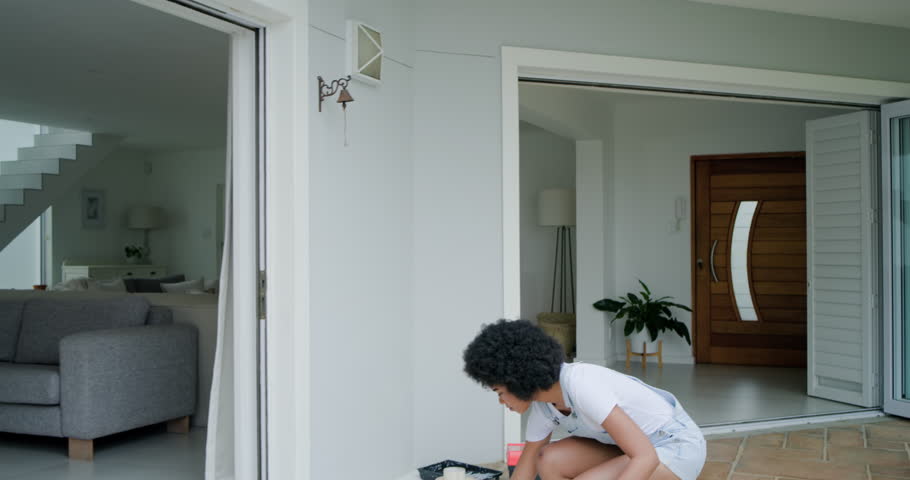 African American woman noticing loose wall bell, preparing toolbox, adjusting with tool, copy space. Porch, entryway, maintenance, repair, diy, toolkit, sunlit