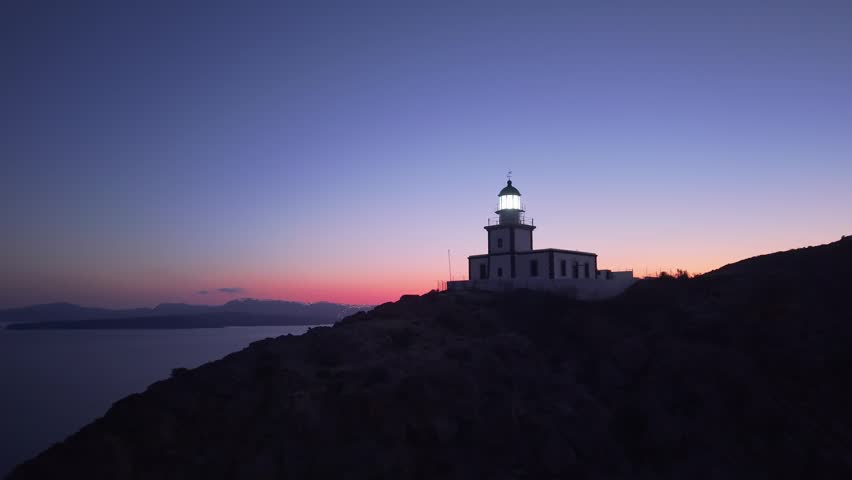 Santorini lighthouse sending a beacon over the Aegean Sea at twilight, capturing the calm waters, dramatic cliffs, and serene evening atmosphere.