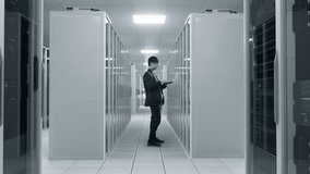 Asian Male Information Technology Specialist Monitors Server Performance on a Laptop in a Modern Data Center, Inspecting Racks and Managing Infrastructure, Ai Systems, Software, and Uptime. - Powered by Shutterstock - Get 15% off with code: PIKWIZARD15