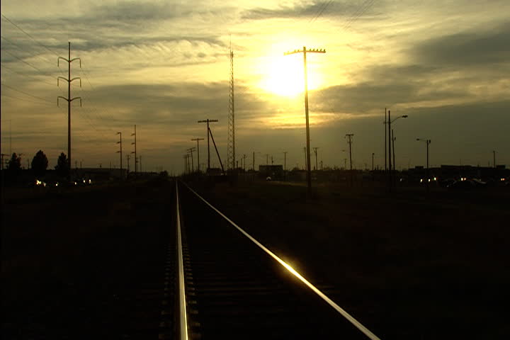 Sunset behind telephone poles glints off railroad tracks in Midland, Texas.
