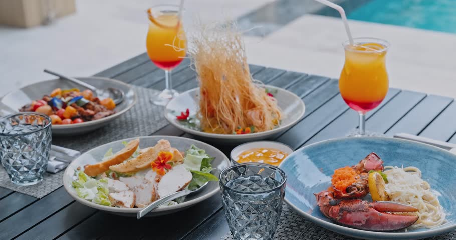 Lobster pasta with Caesar salad and cocktails sitting on wooden table, Homarus americanus served in outdoor restaurant, high-end travel gastronomy, luxury summer vacation dining