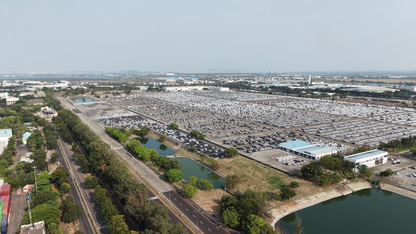 Top view of a large car manufacturing facility with rows of newly produced cars parked and ready for dispatch. The organized layout highlights automotive production, logistics, and distribution operations at scale.
