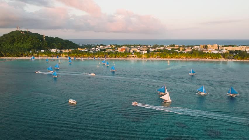 Tourist boats over turquoise water. White sandy beach with sunset reflection. Boracay, Philippines.