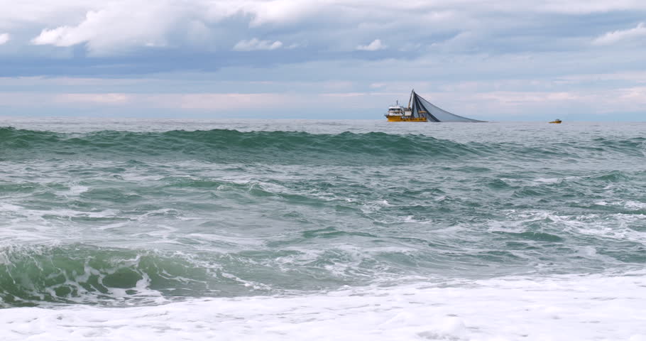 Footage of fishing boat fishing in wavy sea.