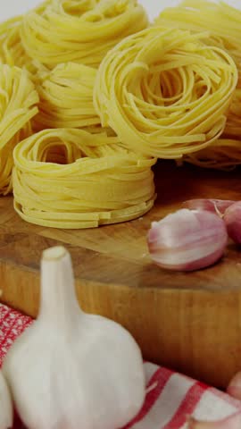 Vertical video: HUD appearing, intensifying, targeting pasta garlic tomato for food tech mapping. Noodles, cloves, red, wooden, countertop, napkin, vertical video