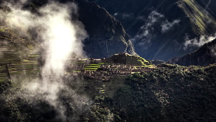 Ancient Inca citadel of Machu Picchu being revealed through moving clouds and fog in Andes mountains, Peru. Aerial drone