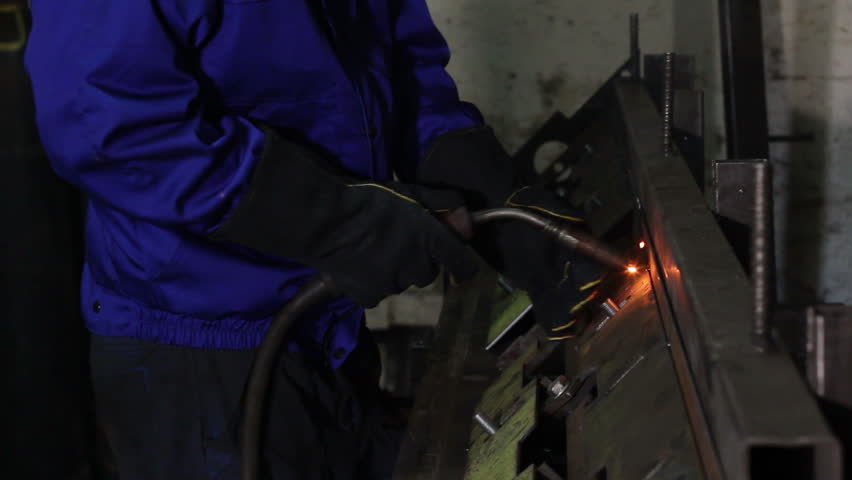 Welder with torch is welding metal on construction site