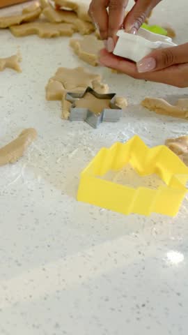 Vertical video: Picking cutter, two hands cutting dough on kitchen top with star cutter for cookies. Baking, collaboration, pastry, countertop, culinary, cozy, vertical video