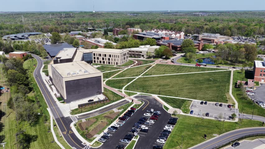 Aerial view of Bowie State University campus in Maryland USA with modern academic buildings, green open lawns, pathways and parking areas in bright spring daylight.