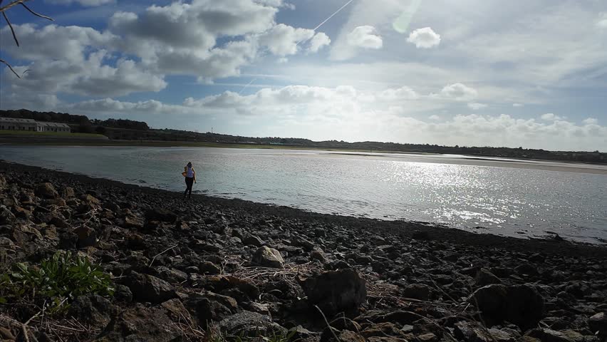 A woman walks on the evening seaside wearing yellow jacket