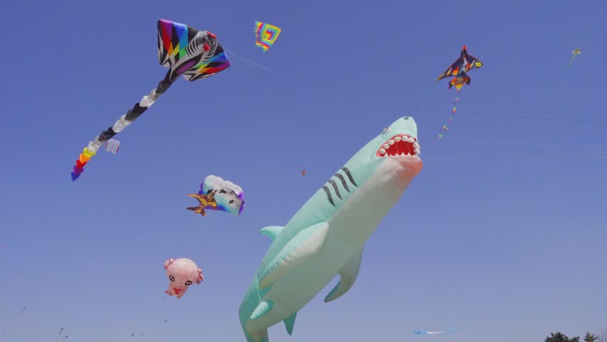 Large colorful inflatable kites shaped like sharks and sea creatures soar in a clear blue sky during a cultural festival in Puebla Mexico.