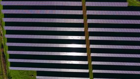 A solar panel array covers a large field. The panels are arranged in rows, capturing sunlight to produce electricity. The field is green, and the sky is clear. - Powered by Shutterstock - Get 15% off with code: PIKWIZARD15