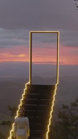 Elevated Tranquility A Woman Ascends an Illuminated Staircase Against the Evening Sky in Costa Rica