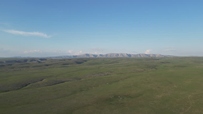 A vast, flat green plain extending toward low hills on the horizon.