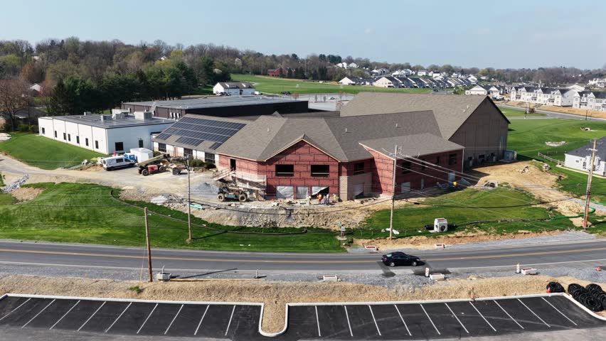 Large church building under construction with workers, vehicles and materials in suburban area near Lancaster Pennsylvania, showing community development and architecture in United States. Aerial view