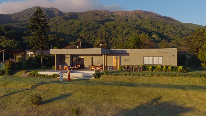 Aerial View of a Modern House in El Salvador with a Mountain Range Background. Couple Walking around their new property