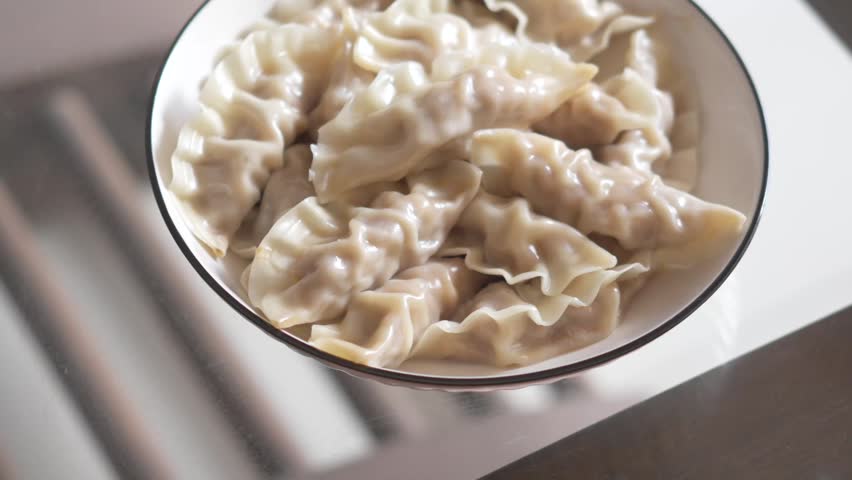 Steaming Dumplings in a White Bowl with Black Rim, Close-Up Food Photography