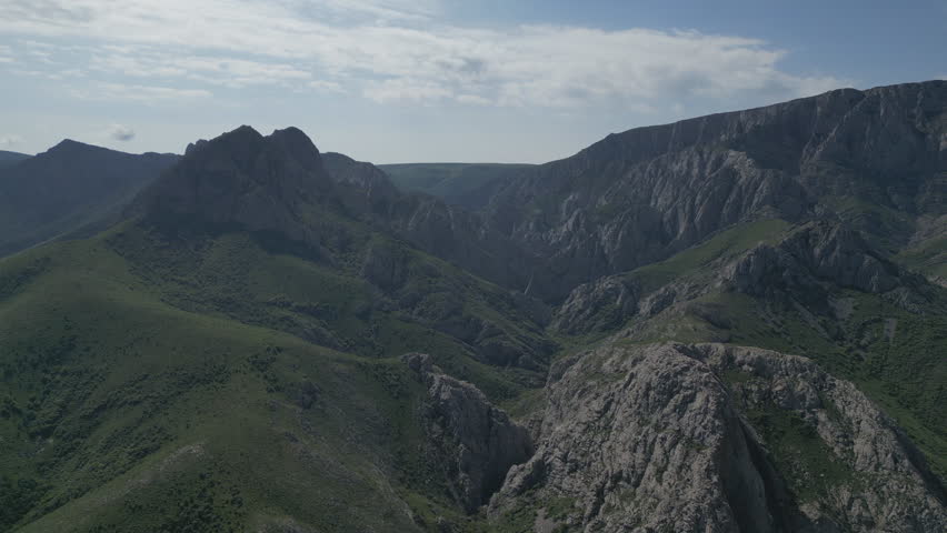 Aerial view of jagged, dark mountain peaks and ridges under a cloudy sky.