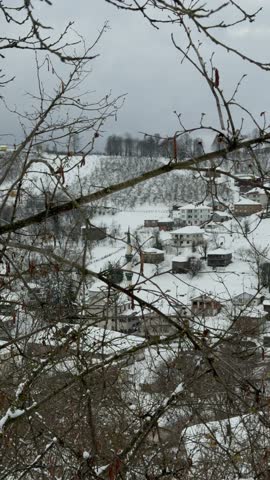 Beautiful 4K cinematic footage of a quiet village under heavy snow. Traditional houses and a mosque with a minaret are scattered across a white hillside in a peaceful winter landscape.