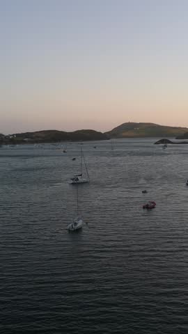 Tranquil coastal scene as the sun sets, illuminating distant green hills.