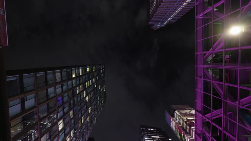 Low angle night view of modern skyscrapers with colorful lights in Manhattan New York City, urban architecture and vibrant cityscape.