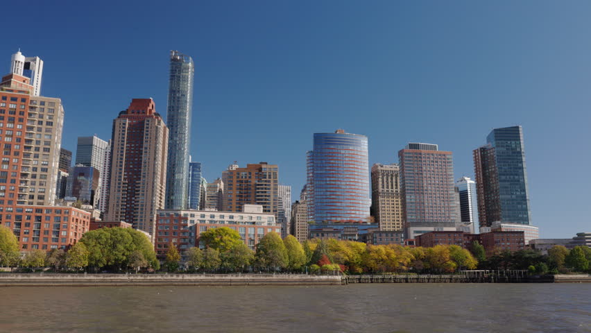 Jersey City skyline across Hudson River near New York City, modern waterfront towers and urban architecture on sunny day, USA.