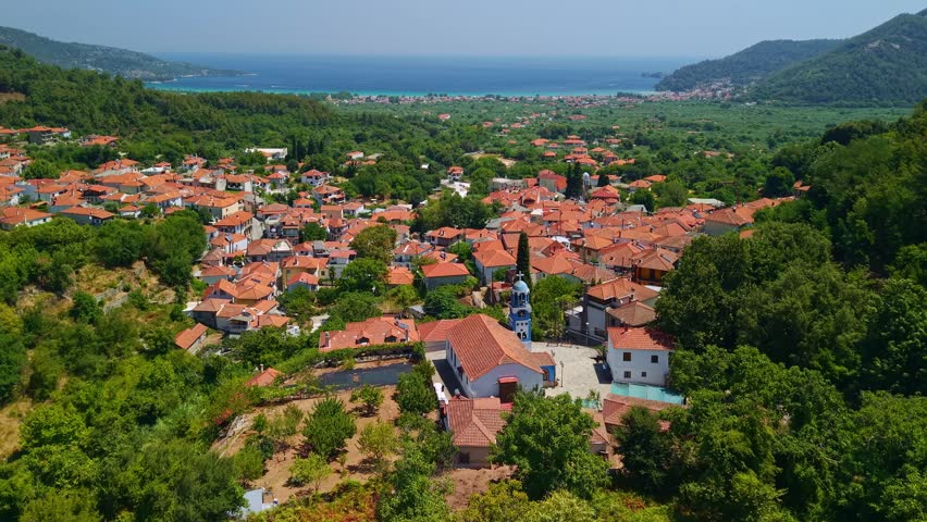 Aerial perspective of the traditional mountain village of Potamia, surrounded by lush green forests and rugged peaks of the Marble mountains on Thassos island, Greece