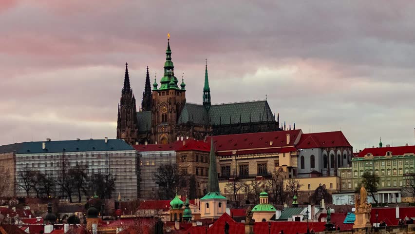 Prague. A panoramic view of a cityscape during twilight, with a focus on a large, ornate cathedral with green spires and a clock tower.