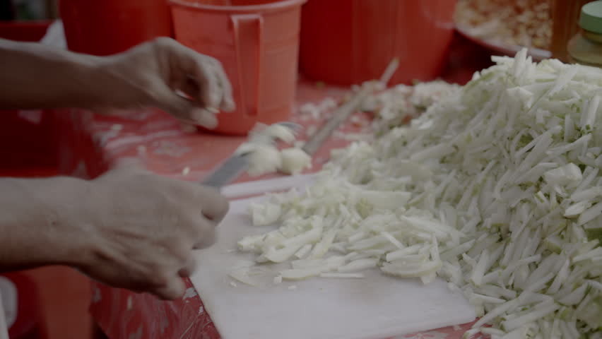 Close up of hands cutting Cucumber  in busy food stall
