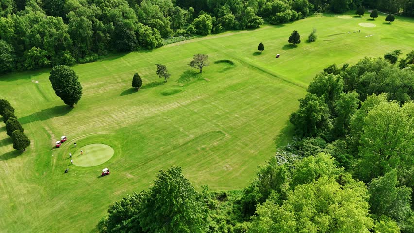 Beauty of the springtime weather cascading over the surrounding fields while several people appear to be engaging in a leisurely sport.