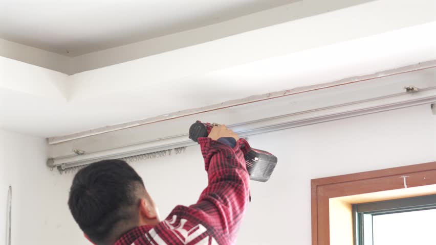 Man in Red Plaid Shirt Installing Ceiling Rail or Track Lighting Fixture Near Window