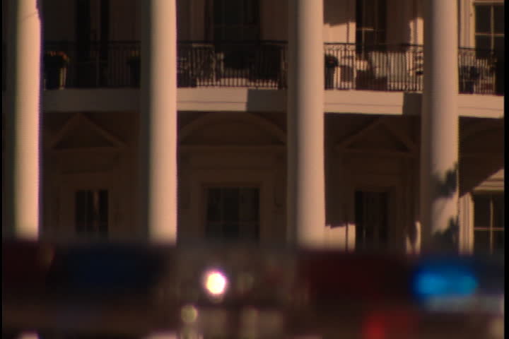 WASHINGTON, D.C. - SEPTEMBER 24, 2003: MS Truman Balcony, camera zooms out to show cars passing in front of the White House South Portico with top of police car in foreground.