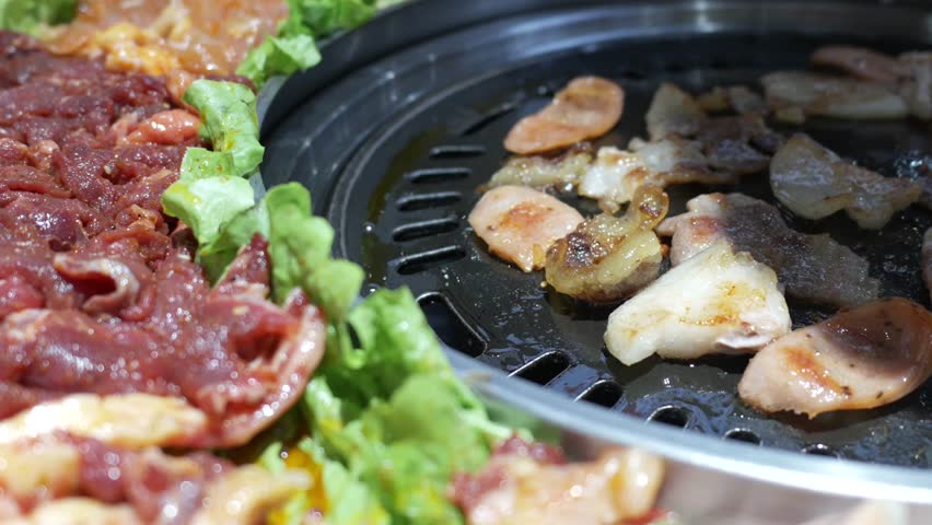 Korean BBQ Feast with Marinated Meat, Grilled Slices, and Fresh Lettuce Wraps on Hot Grill