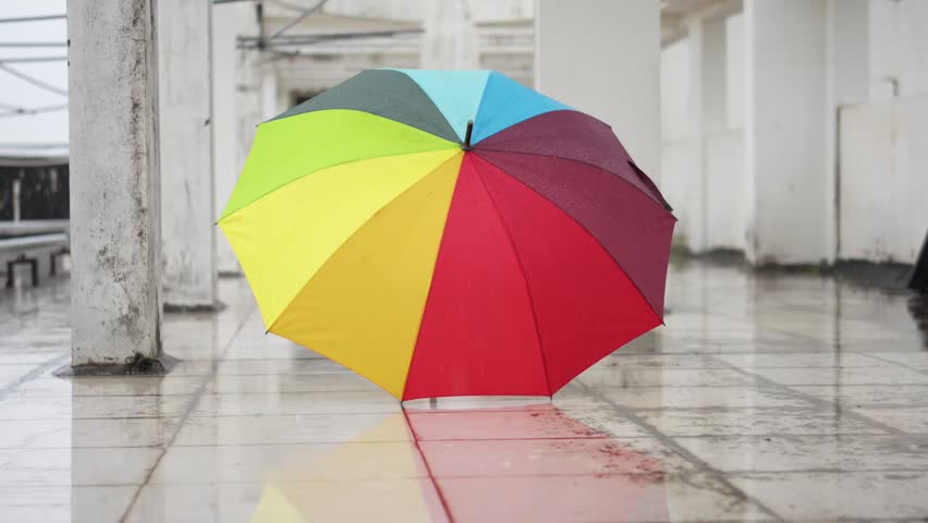 Colorful Rainbow Umbrella Standing on Wet Tile Floor in Abandoned Building Corridor