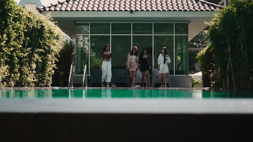Four young asian friends sitting by the swimming pool
