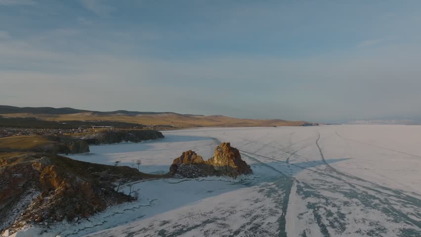 Drone footage of Shamanka Rock on Olkhon Island, overlooking the frozen surface of Lake Baikal with ice cracks and tracks, Irkutsk Oblast, Russia