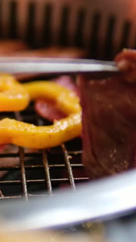 korean grill cooking beef slices and yellow pepper close up barbecue scene 