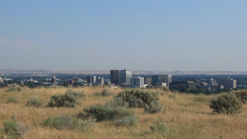 The downtown Boise skyline rises above a foreground of dry summer grasses and sagebrush in this static, wide-angle establishing shot of Idaho