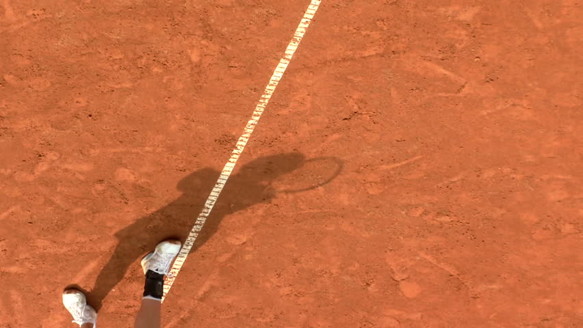 Shadow of a tennis player during serve motion in a clay court