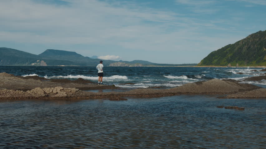 Lonely man stands on the coast of Kunashir Island near the cape of Stolbchaty, Russia