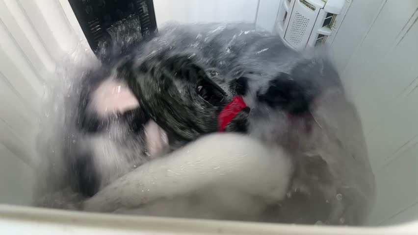 Close up top view of laundry washing in a machine with soap suds